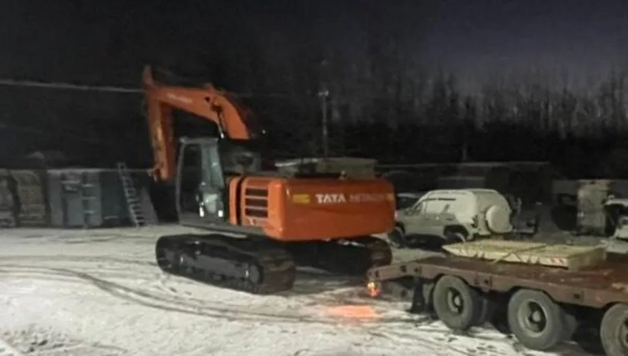 Ночная выгрузка экскаватора с трала на заснеженной площадке